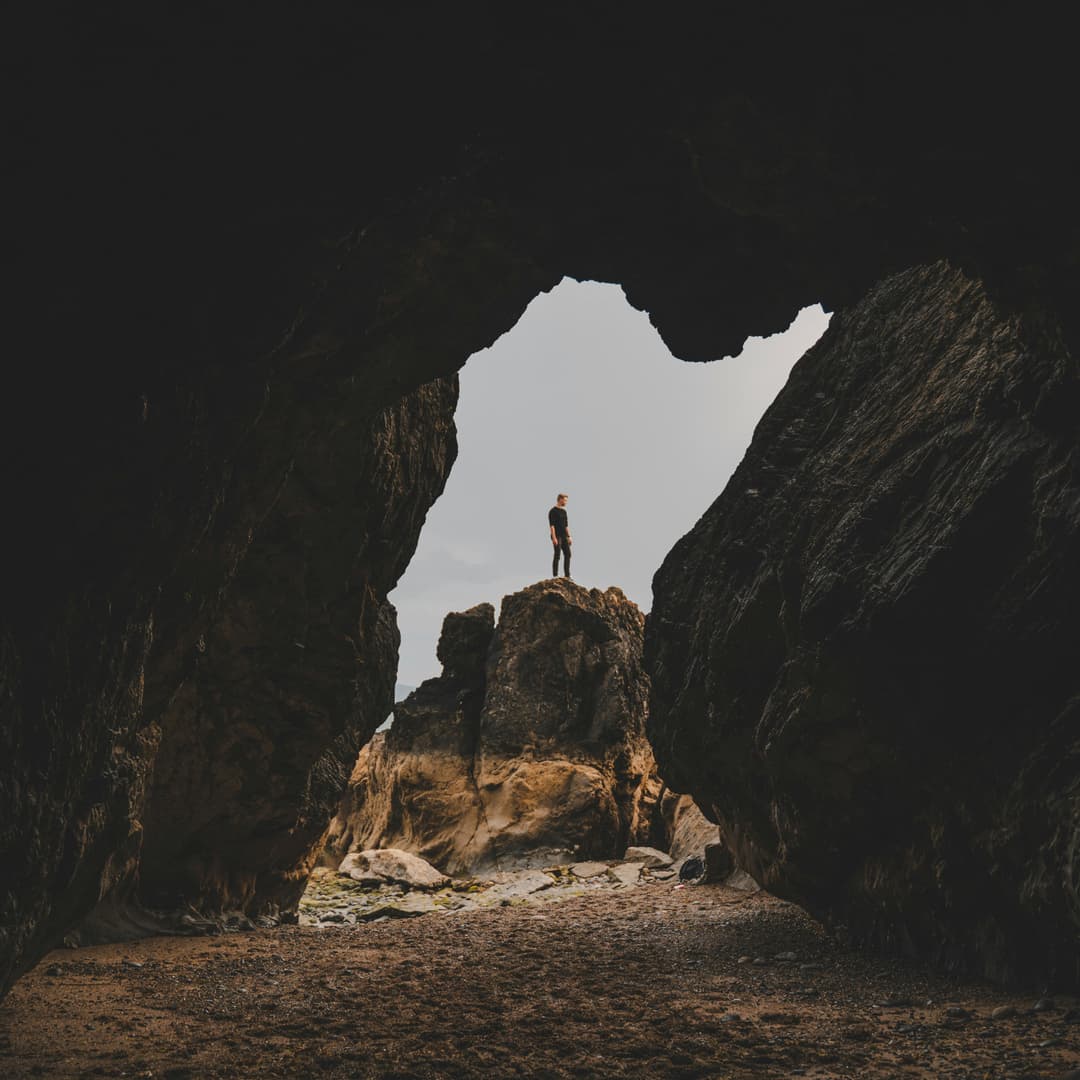 Person in Black Shirt Standing on Rock Formation